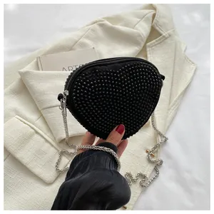 Close-up of black heart-shaped bag with dense stud textures and silver chain strap