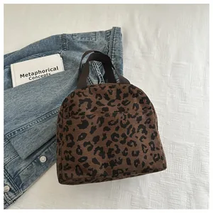 Close-up of leopard print tote lunch bag with brown canvas straps and corduroy texture