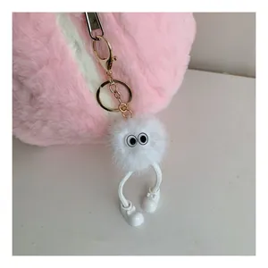 Detail of creative white plush doll charm with cartoon eyes and tiny shoes hanging on a bag
