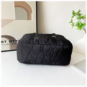 Détail de couture coeur sur le sac bandoulière léger en nylon noir pour voyage