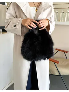 Sac à main chic en fausse fourrure noire porté par un modèle en tenue automne-hiver