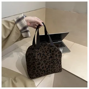 Detail of leopard print canvas handbag with dual brown straps for casual use