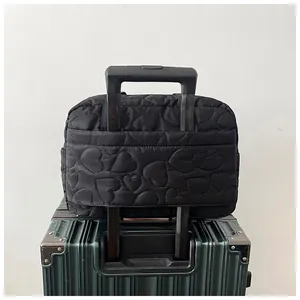 Détail du sac de voyage matelassé noir avec passant pratique pour poignée de valise