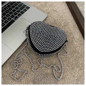 Macro detail of heart-shaped handbag with silver rhinestones and metal chain strap
