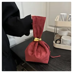 Close-up of vintage burgundy suede bucket bag with elegant gold metal ring buckle detail