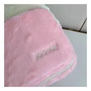 Detailed view of pink plush fabric texture with white stitching and brand embroidery