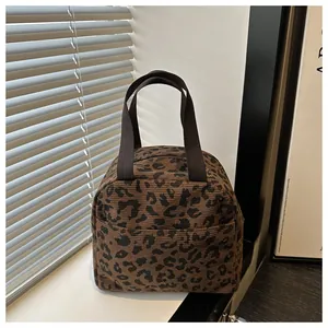 Detailed macro view of leopard print corduroy lunch bag with sturdy brown handles