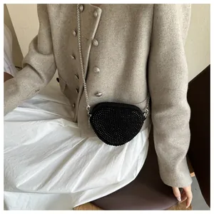 Detail view of heart-shaped black crossbody bag with rhinestones and silver chain