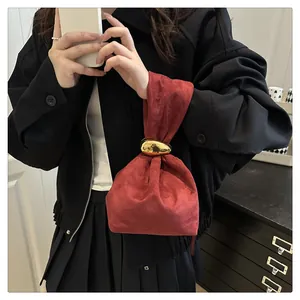 Detail of burgundy suede bucket bag with gold pebble metal buckle and pleated design