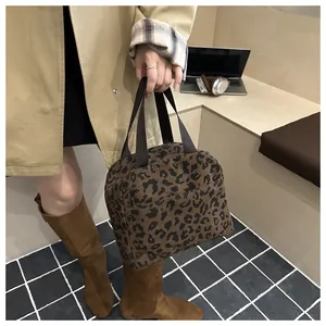 Detailed close-up of leopard print corduroy handbag with sturdy brown handles and texture
