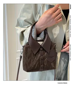 Detail of shirt-style dark brown leather handbag with collar, buttons and embossed pocket