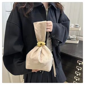 Detail of beige pleated handbag featuring a distinctive gold metallic ring attachment