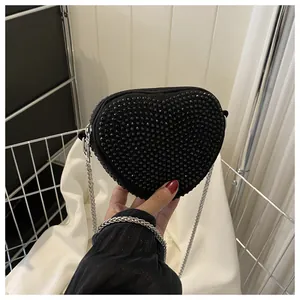 Detailed view of a black heart-shaped crossbody bag with glittering rhinestones and silver chain