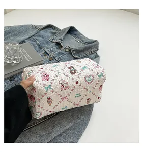 Vue détaillée d'une trousse à maquillage matelassée crème avec des illustrations mignonnes