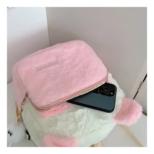 Close-up of plush pink and white mini backpack showing interior capacity with a phone