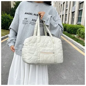 Détail du sac de voyage blanc matelassé avec surpiqûres en cœur et poche zippée pratique