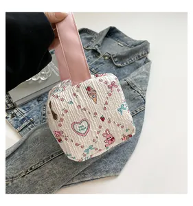 Détail du sac à main en tissu matelassé avec motifs de dessins animés et anse rose