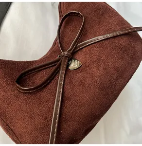 Détail du pendentif en cœur et du nœud sur le sac cabas en daim marron foncé