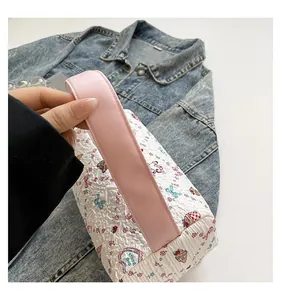 Détail du sac à main matelassé à fleurs avec anses roses sur fond en jean bleu