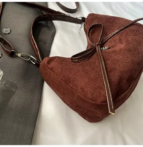 Détail d'un sac cabas en daim marron avec nœud en cuir et éléments métalliques argentés