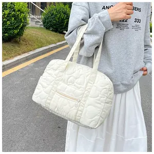 Détail d'un sac à bandoulière matelassé blanc avec motifs de cœurs et poche zippée argentée