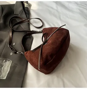 Gros plan détaillé du sac cabas en daim marron avec nœud décoratif sur un costume gris