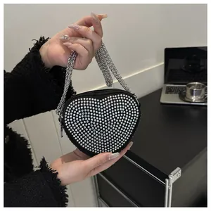 Detailed macro of a heart-shaped black evening bag with silver rhinestones and chain strap