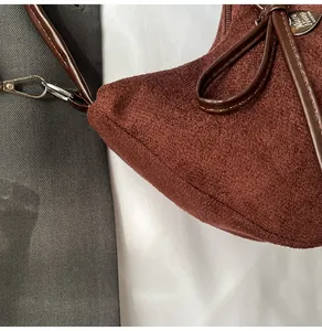 Détail du sac cabas en suède avec nœud en cuir et plaque logo en métal en cœur