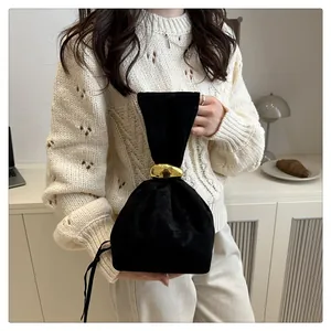 Detail of black velvet bucket bag featuring elegant gold metal ring and soft pleated texture