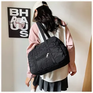 Détail du sac cabas matelassé noir avec motif cœur et poche zippée porté par un mannequin