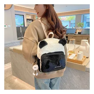 Detail of soft plush panda backpack with black ears and white furry pendant on the side