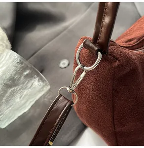 Détail du crochet en métal argenté et texture suédée marron foncé sur un sac cabas