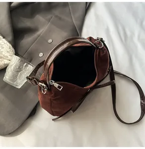 Vue de dessus d'un sac Boston en daim marron avec anses en cuir sur un lit épuré