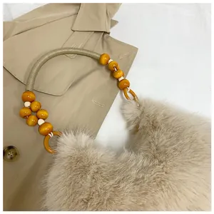 Detail of plush faux fur shoulder bag featuring beaded handle and soft camel texture