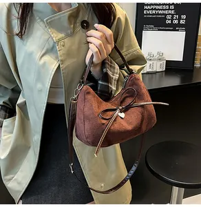 Détail du cabas en daim marron foncé avec nœud et double bandoulière en cuir poli