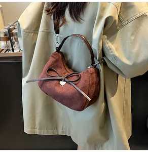 Détail du cabas en daim marron avec nœud en cuir et pendentif cœur argenté