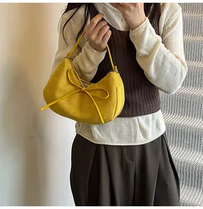 Détail du sac croissant en daim jaune avec un grand nœud et une boucle en métal