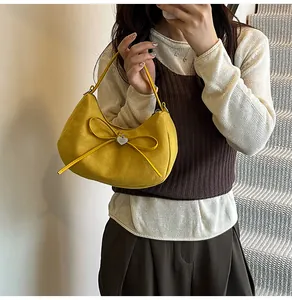 Détail du sac cabas jaune en forme de croissant avec texture suède, nœud et pendentif cœur