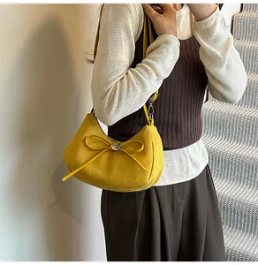 Détail du sac demi-lune en daim jaune avec nœud décoratif et boucle coeur argentée