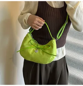 Détail du sac fourre-tout en daim vert avec un nœud décoratif et un pendentif cœur