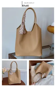 Detail view of khaki tote bag with litchi texture and decorative scarf on handle