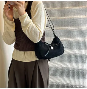 Détail du sac cabas en daim noir avec nœud en cuir délicat et pendentif coeur en argent