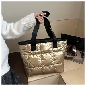 Detail of metallic gold quilted tote bag with black nylon straps in lifestyle setting