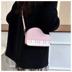 Detail van de roze piano-vormige crossbodytas met stippen gedragen door een model in blazer