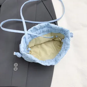 Quilted light blue drawstring bucket bag with textured cloud design and slim strap
