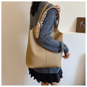 Detail of khaki pebbled leather tote bag featuring a diamond pattern silk scarf accent