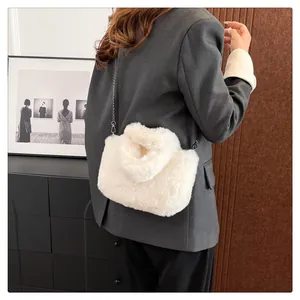 Detailed view of white faux fur crossbody bag with silver chain on model in gray blazer