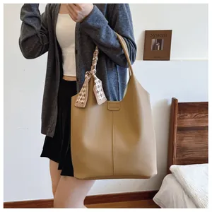 Detail of khaki leather tote with checkered scarf and fashion label in a lifestyle setting
