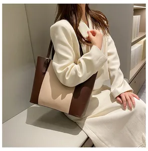 Detailed view of spacious color-block tote bag in brown and cream faux leather with gold hardware