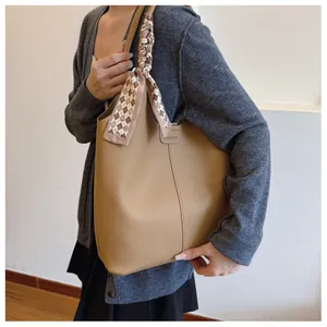 Detail of khaki pebbled leather tote bag with elegant scarf wrapped handle